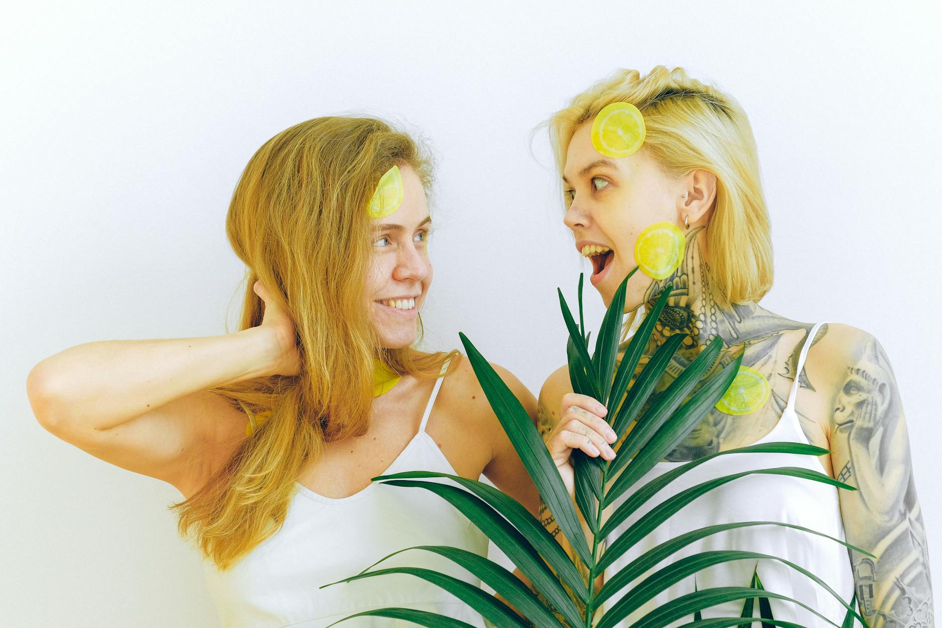 Two women smiling outdoors with lemon slices, expressing calm joy and presence