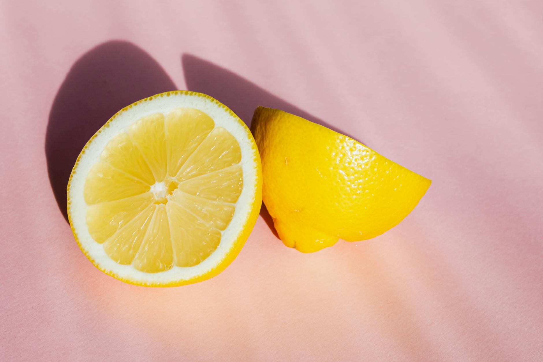 Fresh halves of lemon arranged on a pink background in bright sunlight, symbolizing renewal and freshness after loss