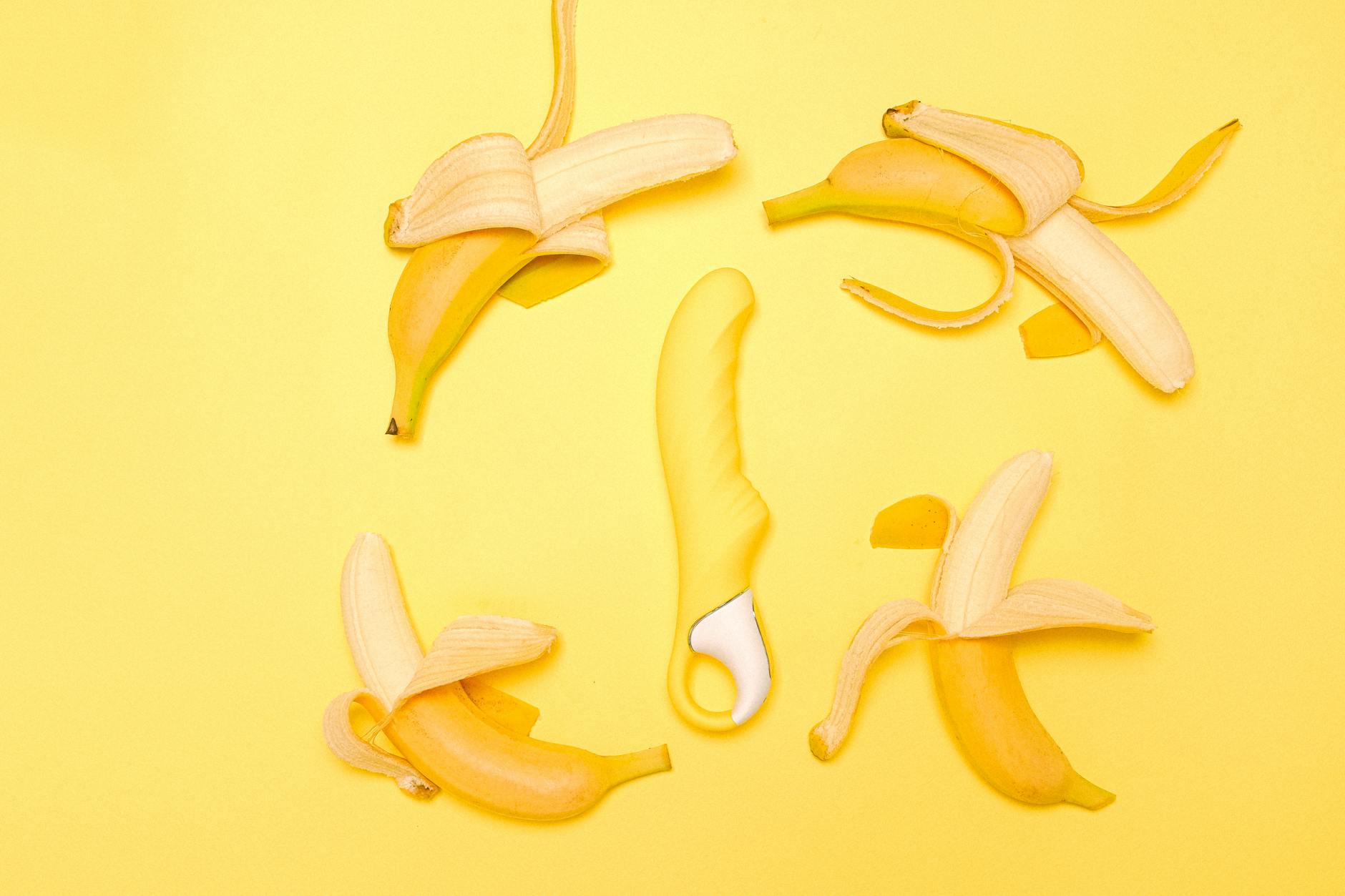 Creative flat lay of a yellow silicone lemon vibrator on a warm yellow background.